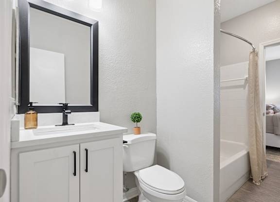 A white bathroom with a toilet, sink, and mirror.