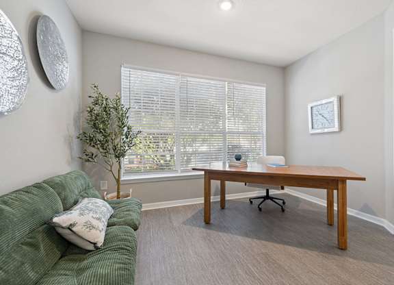 A room with a green couch, a wooden table, and a plant.