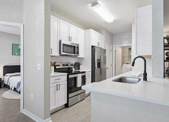 A modern kitchen with a white countertop and stainless steel appliances.
