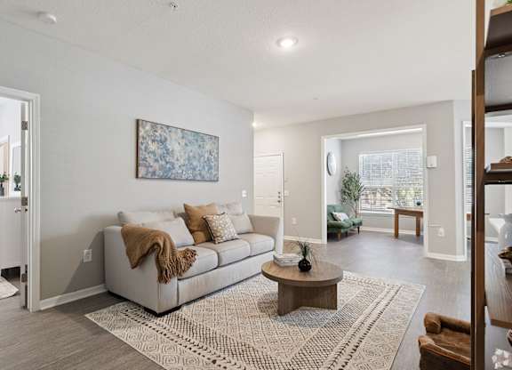 A living room with a couch, a coffee table, and a painting on the wall.
