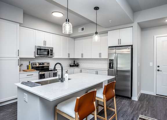 Quartz countertops, trendy tile backsplash and matte black fixtures in model
