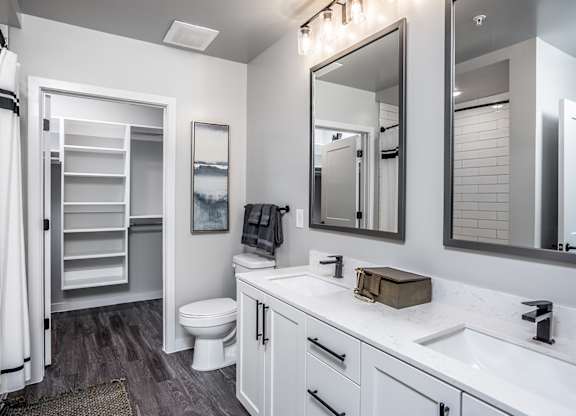 Dual vanities, hardwood-inspired flooring, designer light fixtures and framed mirrors in bathrooms