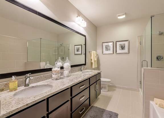 Bathrooms with dual vanities, framed mirrors and granite countertops