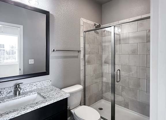 Townhome bathroom with granite countertops, framed mirror and shower