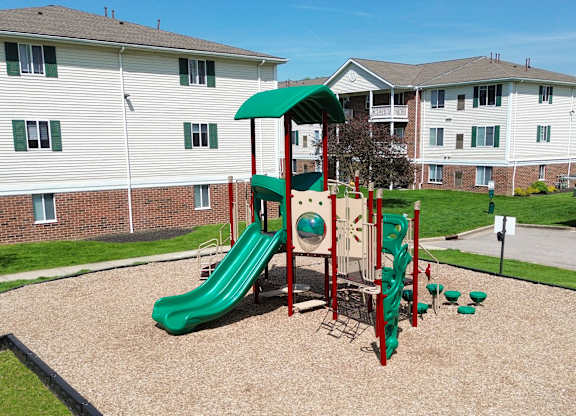 A playground with a green slide and red and green play structure.