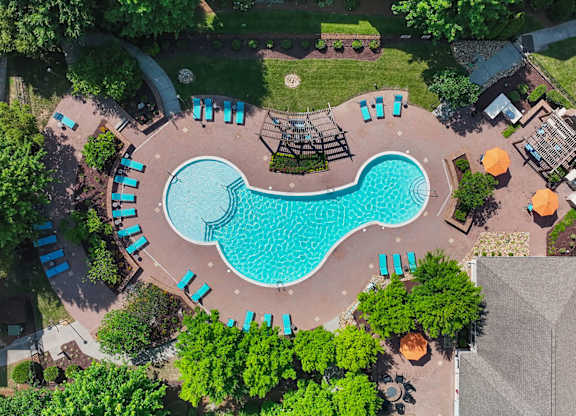 An aerial view of a swimming pool surrounded by trees and lounge chairs.
