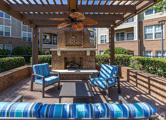 A patio with a fireplace and chairs.