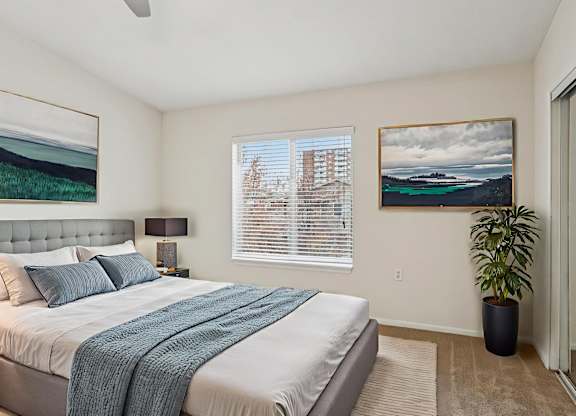 A bedroom with a large bed and a painting on the wall.
