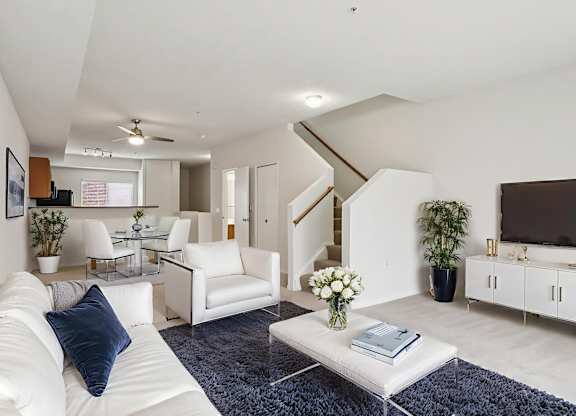 A living room with a white couch and a blue rug.