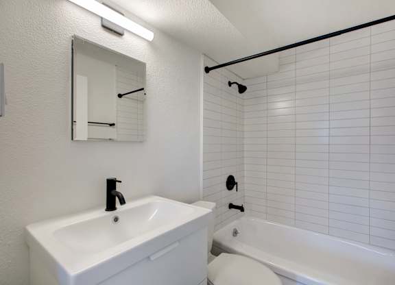 A white bathroom with a sink, toilet, and bathtub.