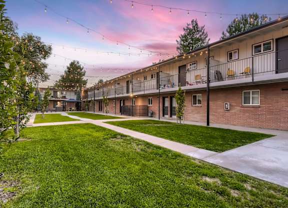 A sunset view of a residential area with apartment buildings and green lawns.