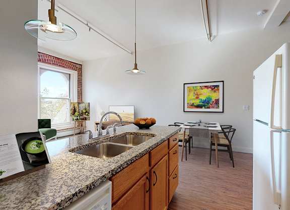 A kitchen with a refrigerator, sink, and a dining table with chairs.