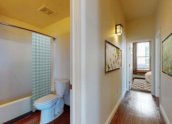 A bathroom with a toilet, a bathtub, and a window with a curtain.