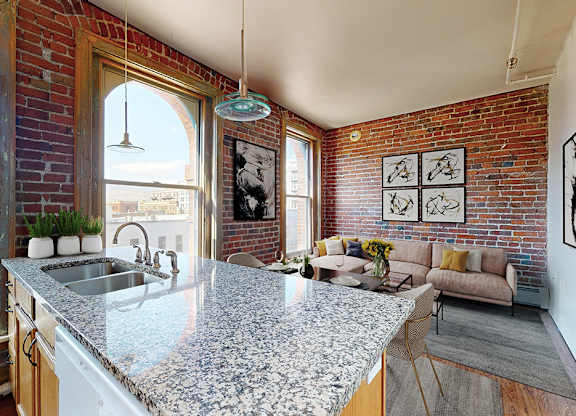 A kitchen with a granite countertop and a brick wall.