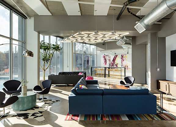 A modern living room with a blue couch and a TV on the wall.