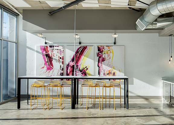 A room with a table and chairs and a painting on the wall.