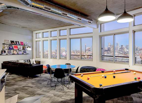 A room with a pool table and a view of the city.