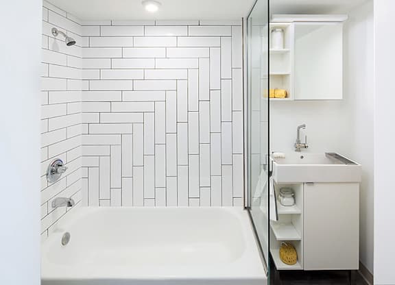 A white bathroom with a white tub and a white sink.