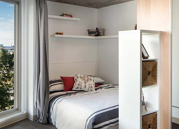 A bedroom with a bed, pillows, and a window with curtains.