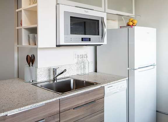 A modern kitchen with a white refrigerator, microwave, and dishwasher.