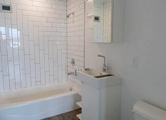 A white bathroom with a tub, sink and mirror.