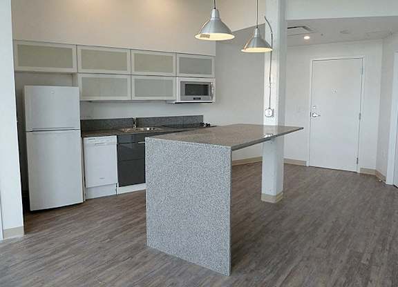 A kitchen with a white fridge and a grey island.