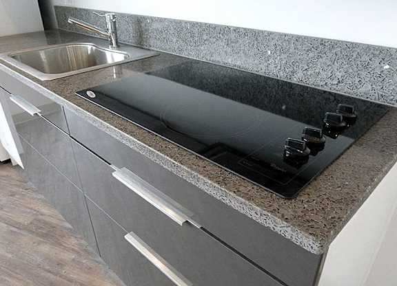 A kitchen counter with a sink and a black cutting board.
