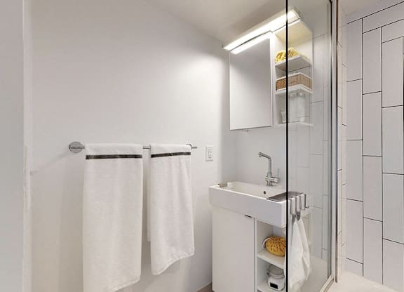 A white bathroom with a sink, mirror, and towel rack.