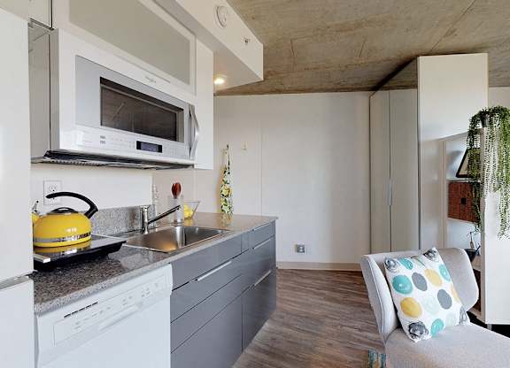 A modern kitchen with a white refrigerator, a yellow kettle, and a grey countertop.
