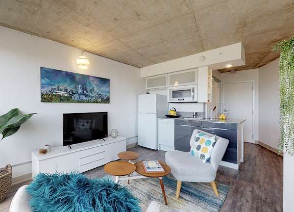 A living room with a blue rug and a painting on the wall.