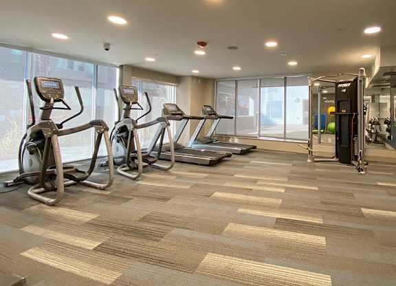 A gym with treadmills, elliptical machines, and dumbbells.