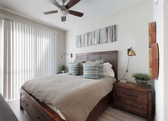 A bedroom with a bed, nightstand, and a ceiling fan.