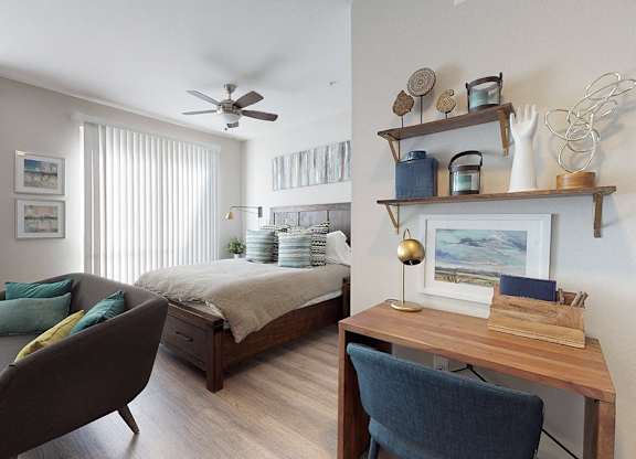 A bedroom with a bed, a chair, and a desk.