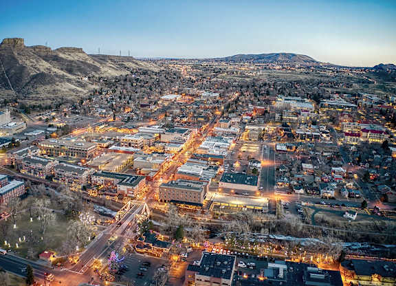 A cityscape at dusk with buildings illuminated and streets bustling with activity.