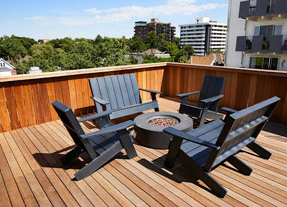 A wooden deck with a fire pit and chairs.