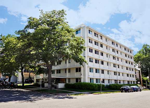 A white building with a tree in front of it.