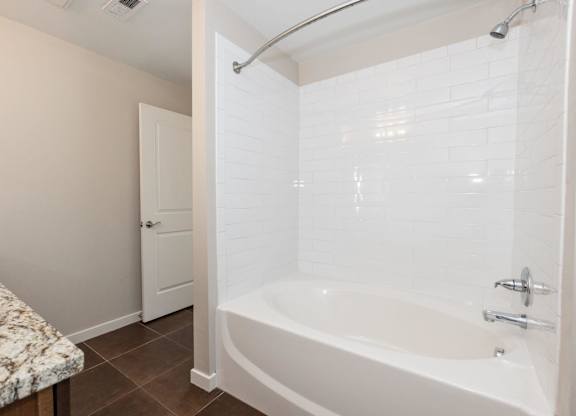 A white bathtub with a shower head and faucet.