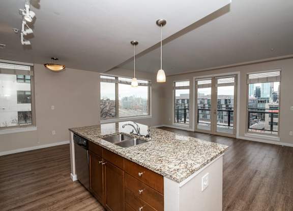 A kitchen with a granite countertop and wooden floors.