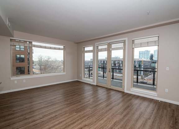 A room with wooden floors and large windows overlooking a cityscape.