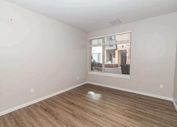 A room with wooden flooring and a window showing an outdoor scene.