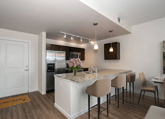 A kitchen with a white island and brown chairs.