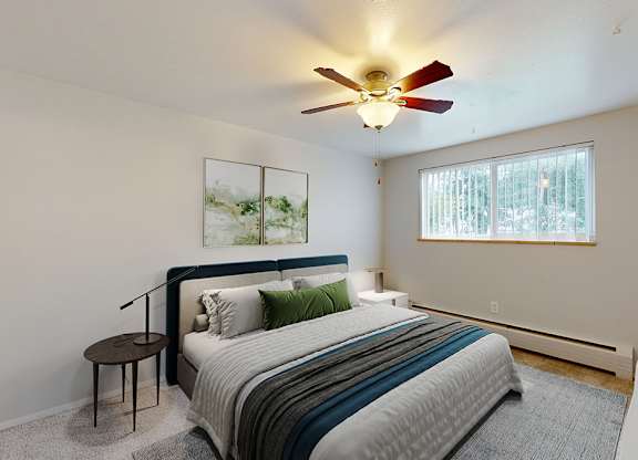 A bedroom with a bed, a ceiling fan, and a painting on the wall.