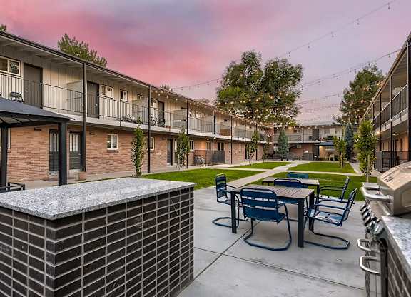A sunset view of a patio with tables and chairs.