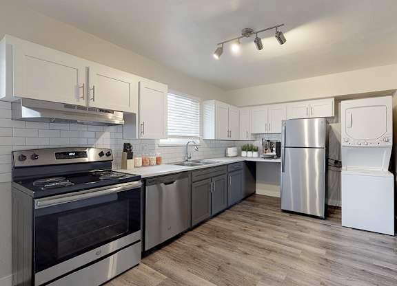 A modern kitchen with stainless steel appliances and wooden floors.
