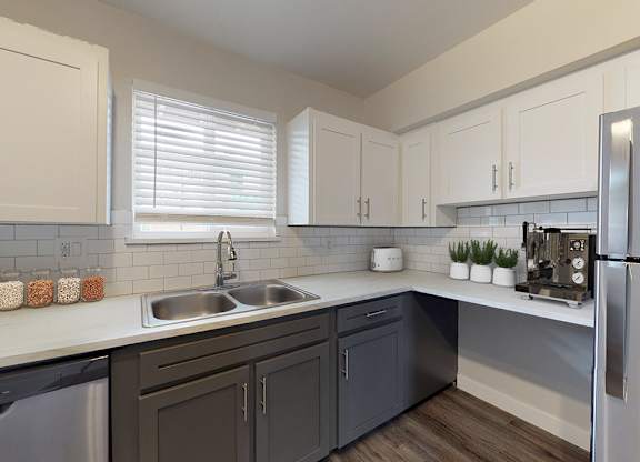 A modern kitchen with a stainless steel refrigerator, sink, and cabinets.