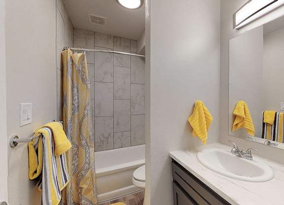 A bathroom with a white sink, a striped towel, and a yellow towel.