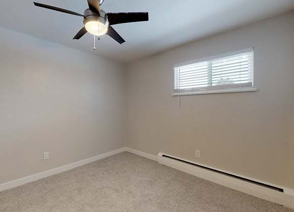 A room with a ceiling fan and a window with blinds.