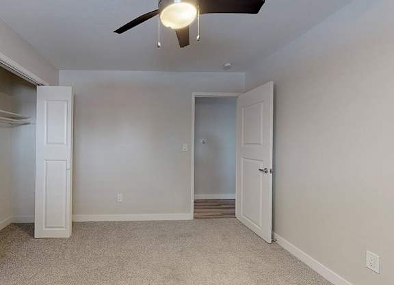 A room with a ceiling fan and two doors.