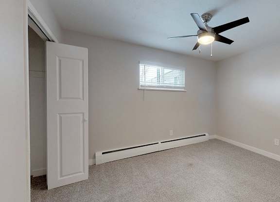 A room with a ceiling fan and a window.