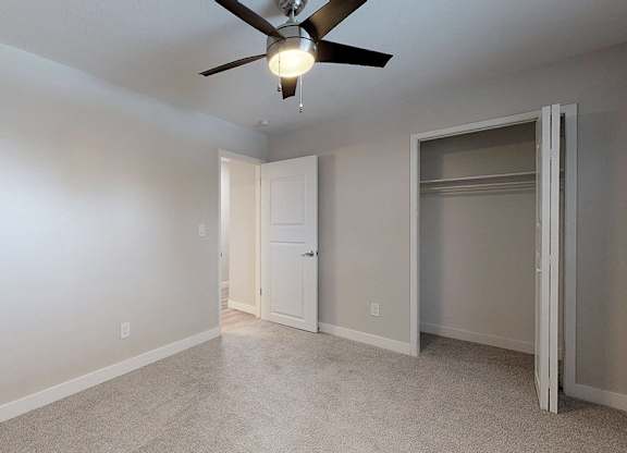 A room with a ceiling fan and a door.